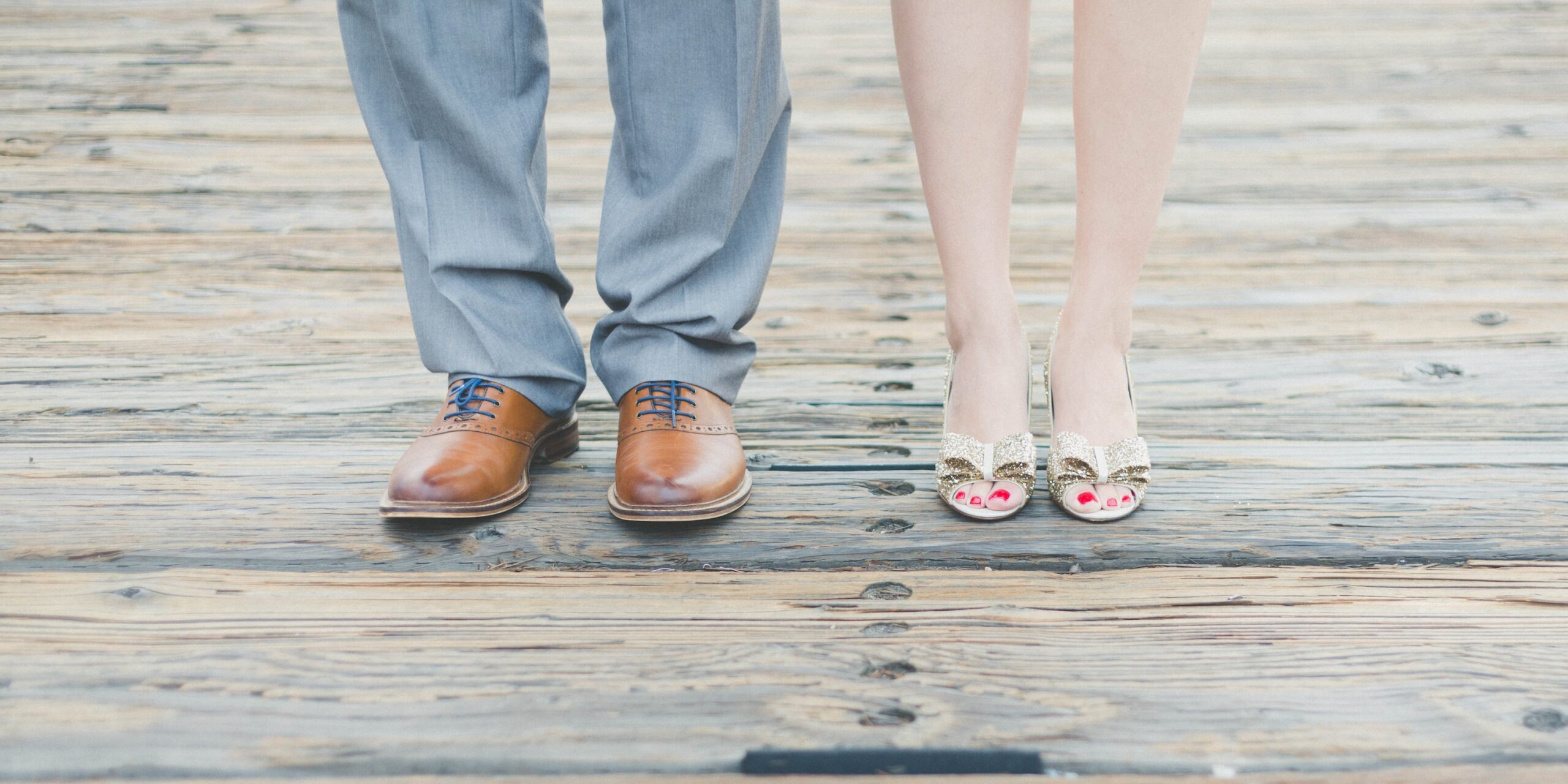man wearing brown leather oxford shoes beside woman wearing gold open-toe sandals