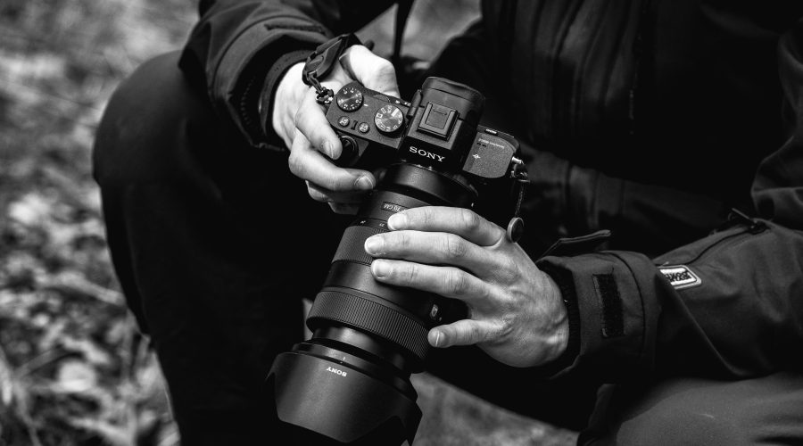 grayscale photo of person holding dslr camera