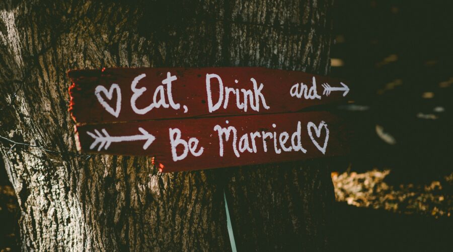 red and white eat, drink, and be married signage near brown tree